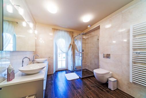 Baño con suelo de madera y paredes en mármol