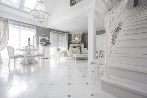 Salón comedor blanco con escalera clásica