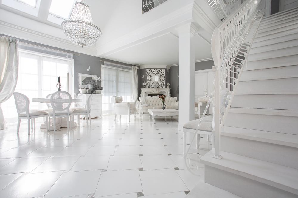 Salón comedor blanco con escalera clásica